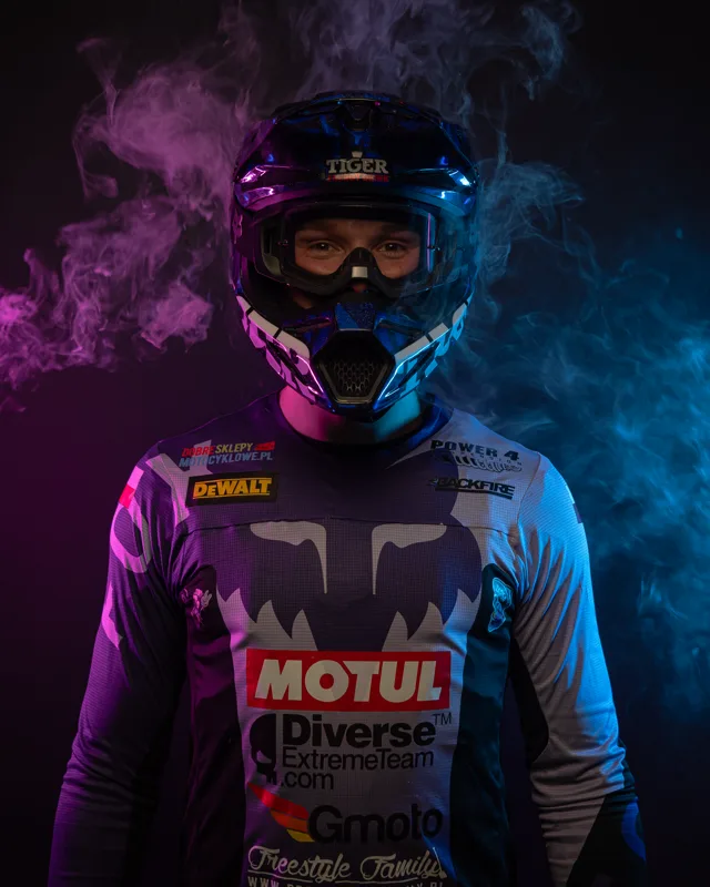 ZAPSA wearing his motocross helmet, lit by purple and blue smoke